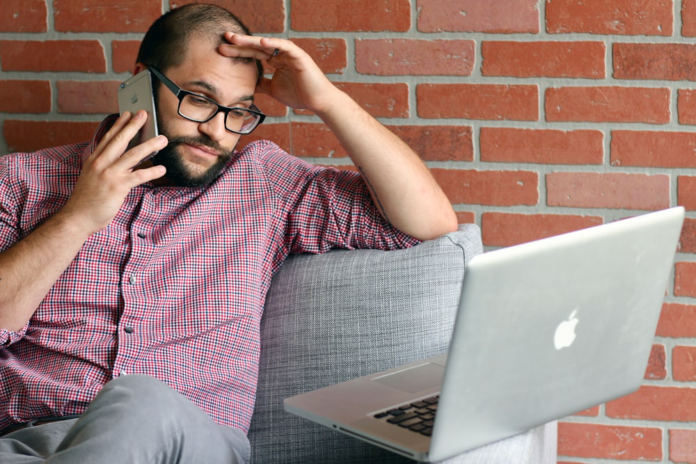 A Visibly Frustrated Man with Low Testosterone on the Phone While Using a Notebook