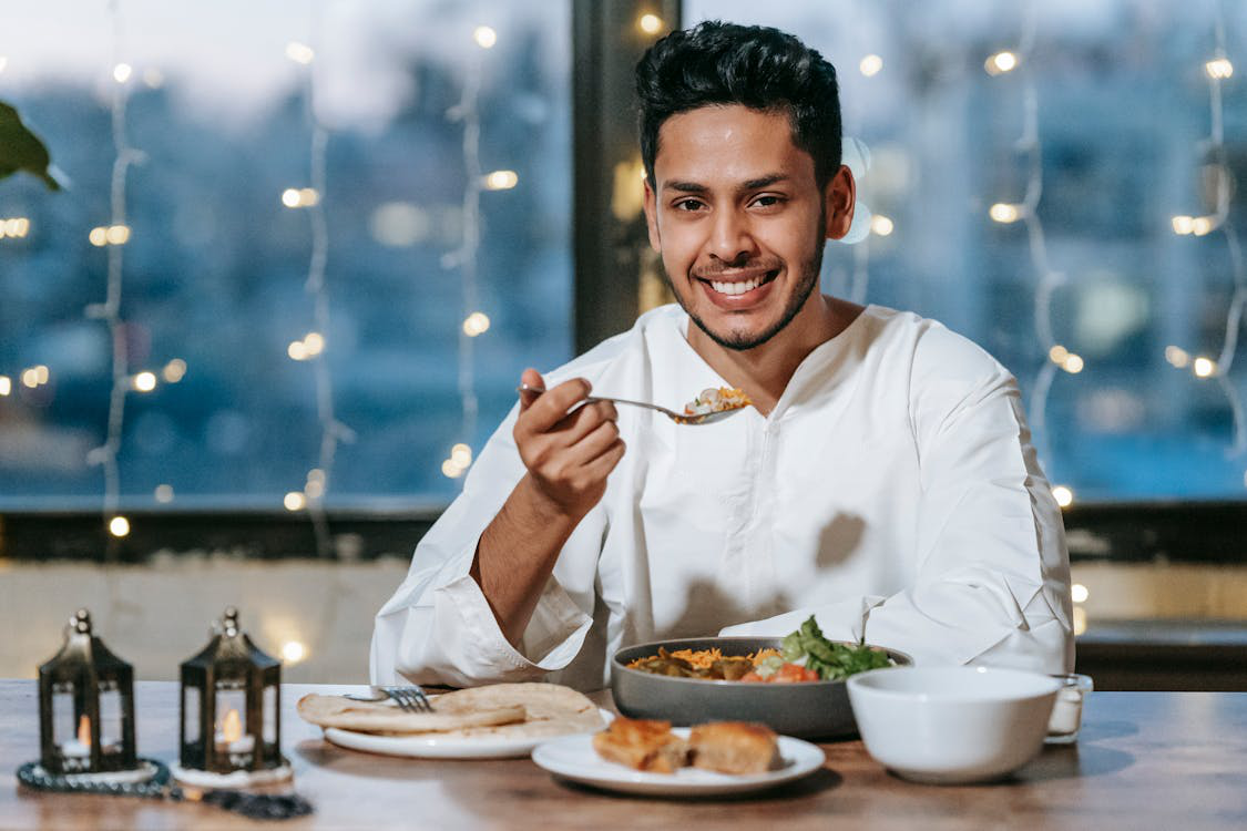 A Man Smiles at the Camera as He Enjoys a Vegetarian Dinner