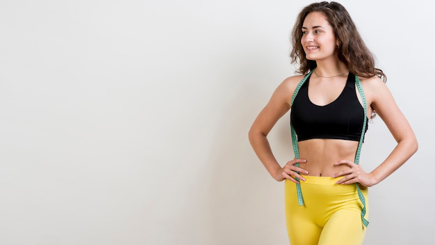 Smiling woman with measurement tape placed around her shoulders, looking motivated.