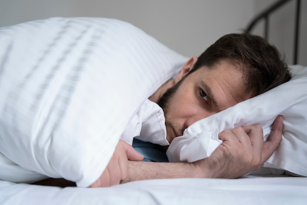 Man lying awake in bed at night, appearing restless and anxious.