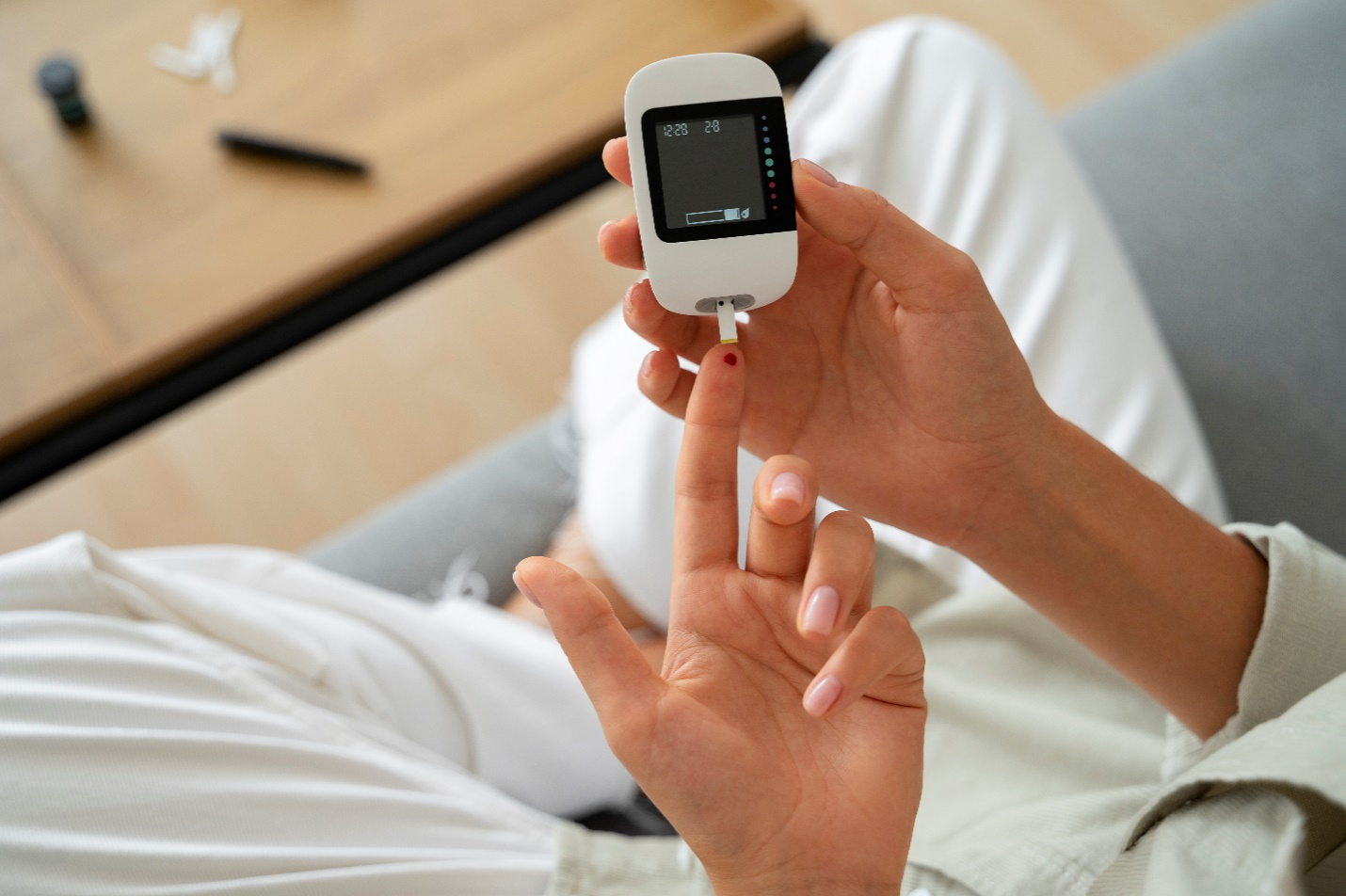 A person’s finger has a speck of blood by a blood sugar monitoring device, signifying the relationship between diabetes and weight gain.