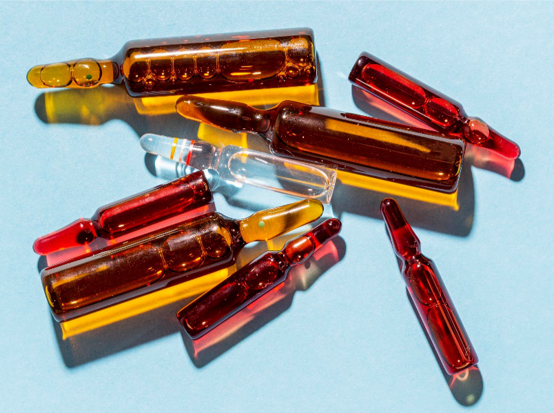 Red vials, representative of Vitamin B12, stand out amongst other yellow and white vials on a light blue surface.