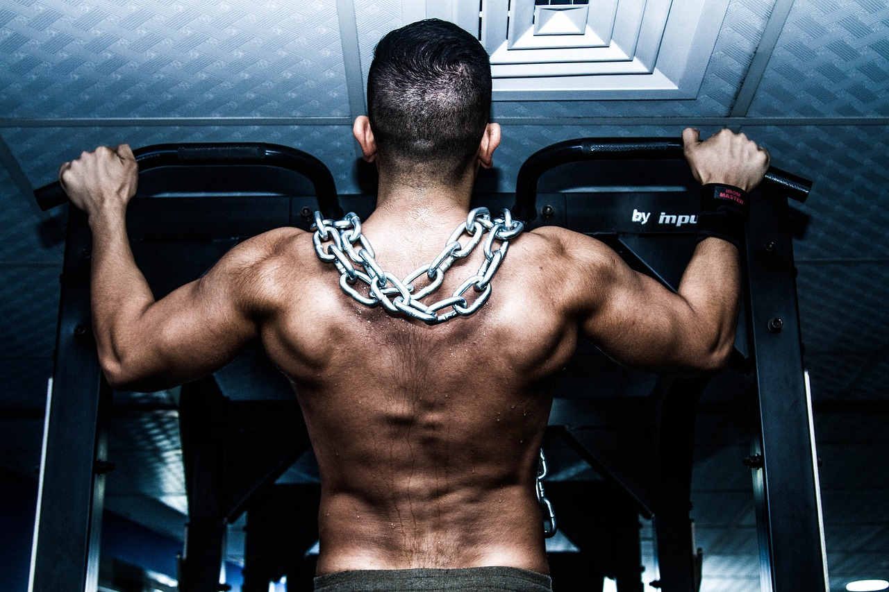 The back of a person with muscles and a chain around their neck