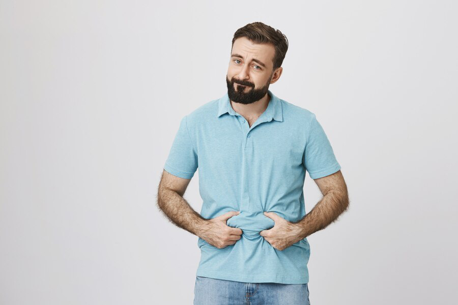  A man in a light blue t-shirt holds his stomach