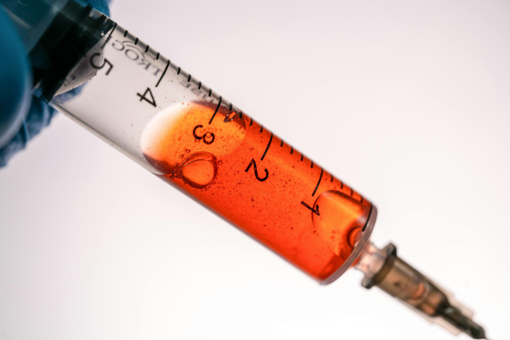 A close-up of a syringe shows 2.5ml of a reddish liquid