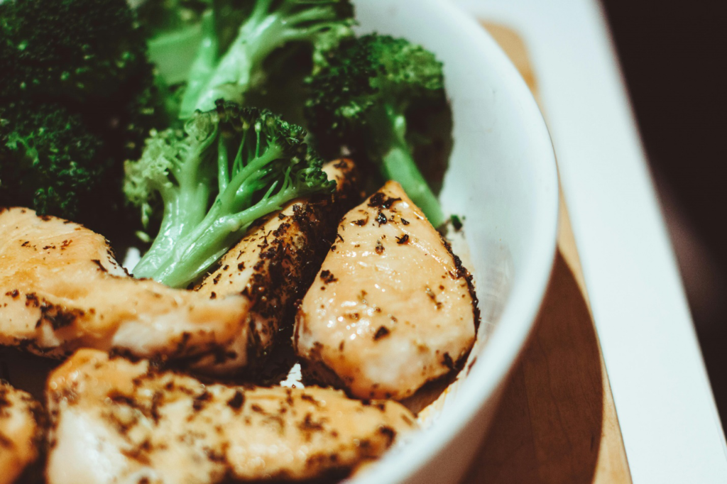 A close-up of a plate of grilled fish and broccoli on a tray