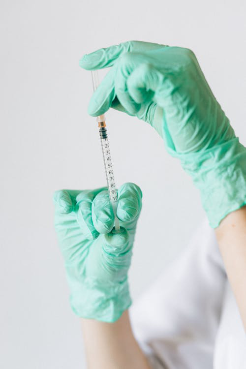 Gloved hands holding a syringe, preparing for a medical weight loss injection.