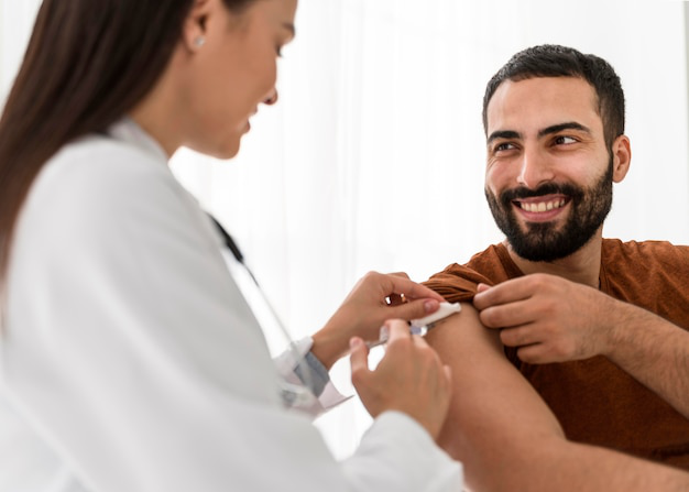 A smiling man receiving an injection shot from a healthcare provider during a consultation.A smiling man receiving an injection shot from a healthcare provider during a consultation.