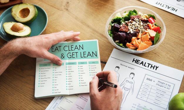 A person planning a healthy diet with a meal plan, salad, and BMI chart for weight management.