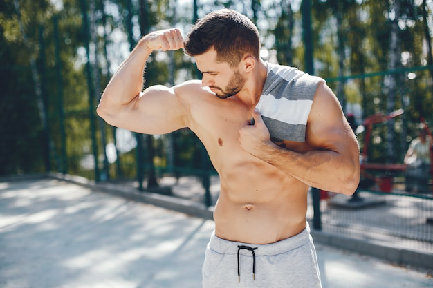 A fit man flexing his muscles outdoors after a workout session.