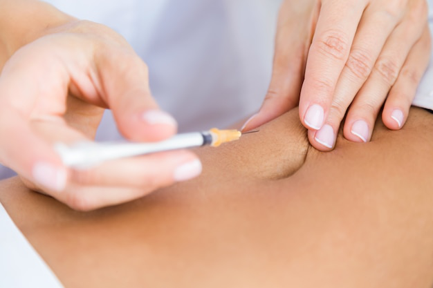 Close-up of a medical professional administering a peptide injection for weight loss and health benefits.