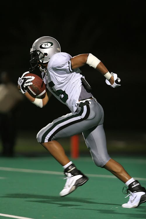 A football player sprinting with the ball, demonstrating speed and power.