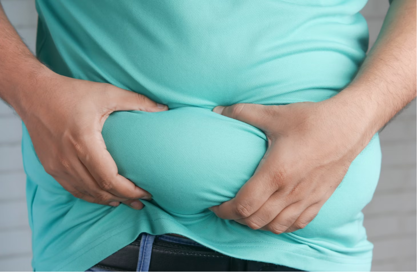  A man holding his stomach with both hands, possibly indicating discomfort.