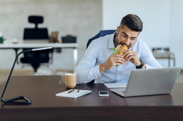 Man multitasking at work while eating lunch at his desk