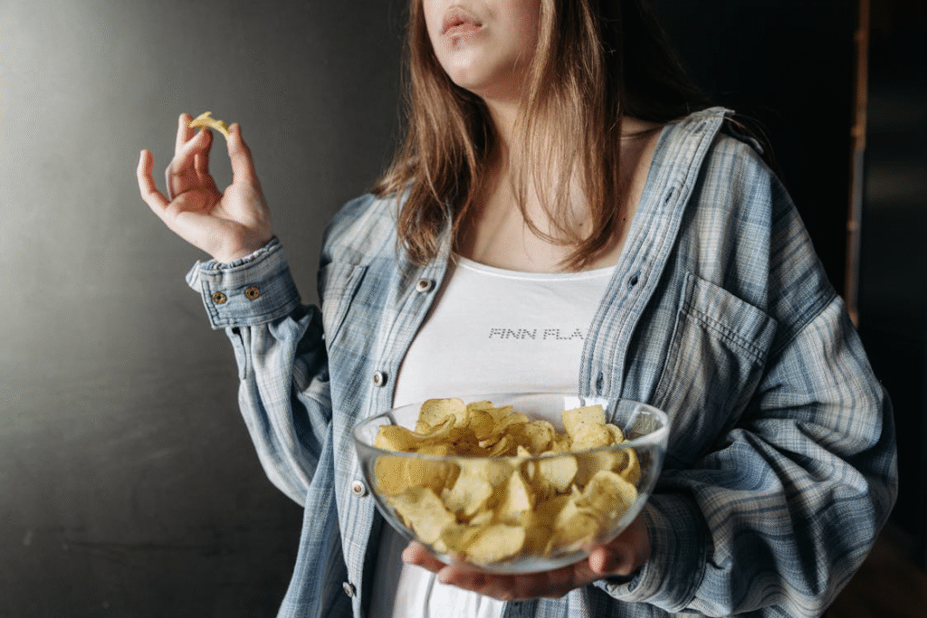 Woman holding a bowl of chips, representing persistent snack cravings