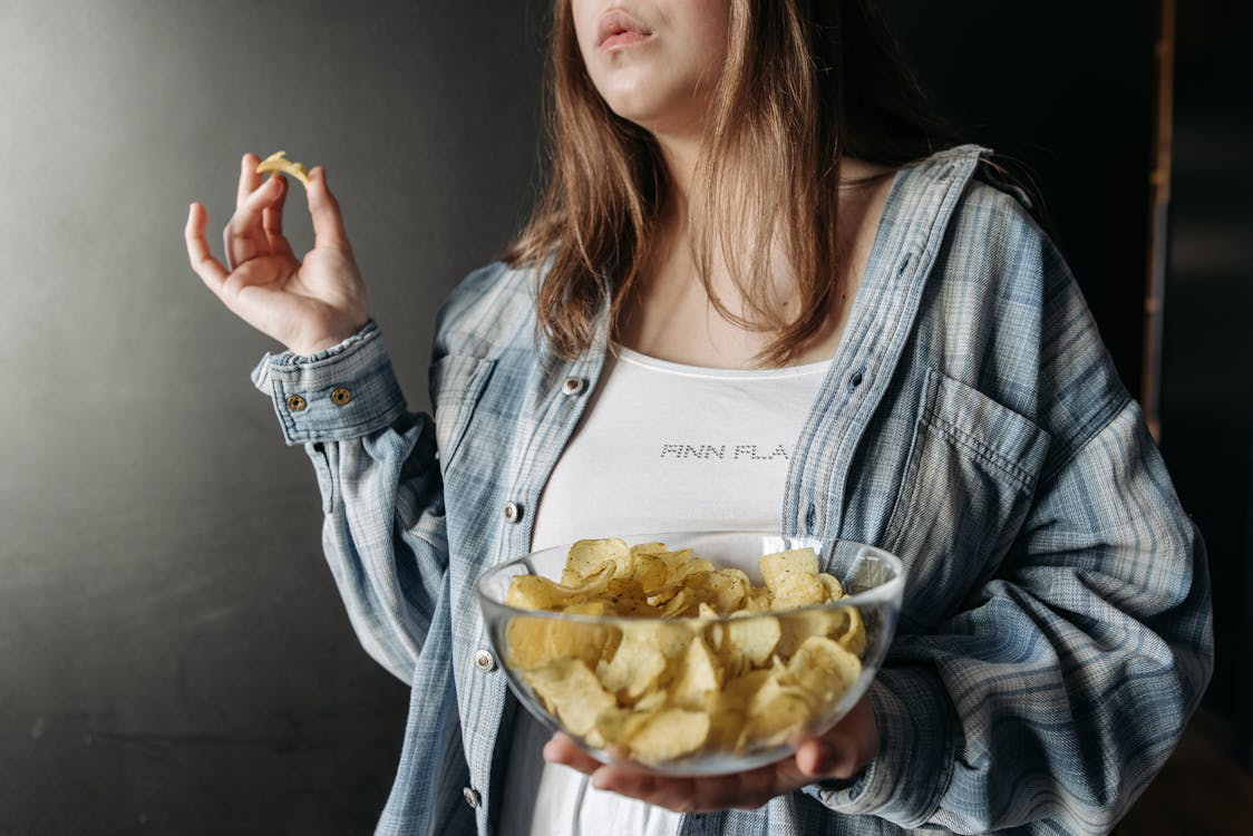 Woman holding a bowl of chips, representing persistent snack cravings