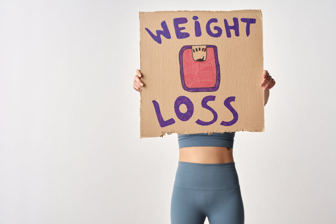 A woman holding a sign that says "weight loss"