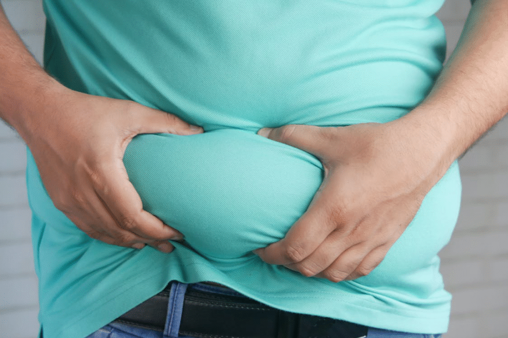 Man holding belly fat, considering lipo injections for weight loss support