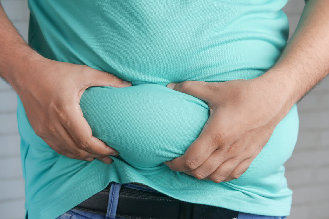 Man holding belly fat, considering lipo injections for weight loss support