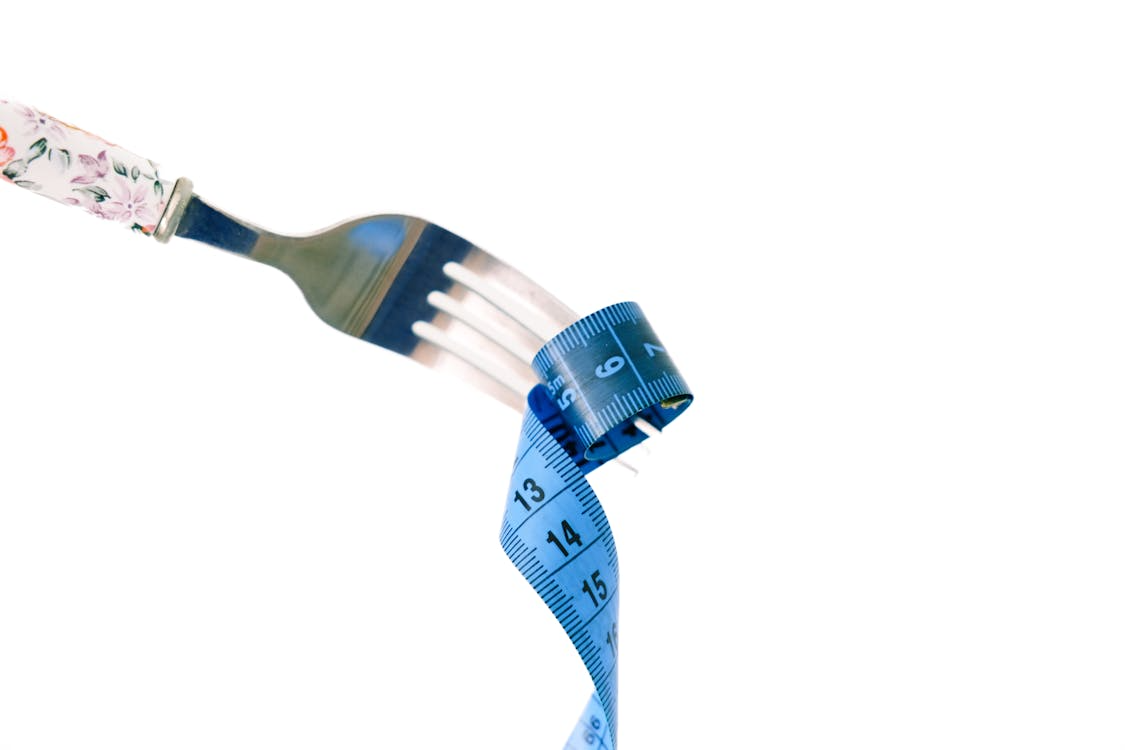 A silver fork has a blue measuring tape wrapped around its tines