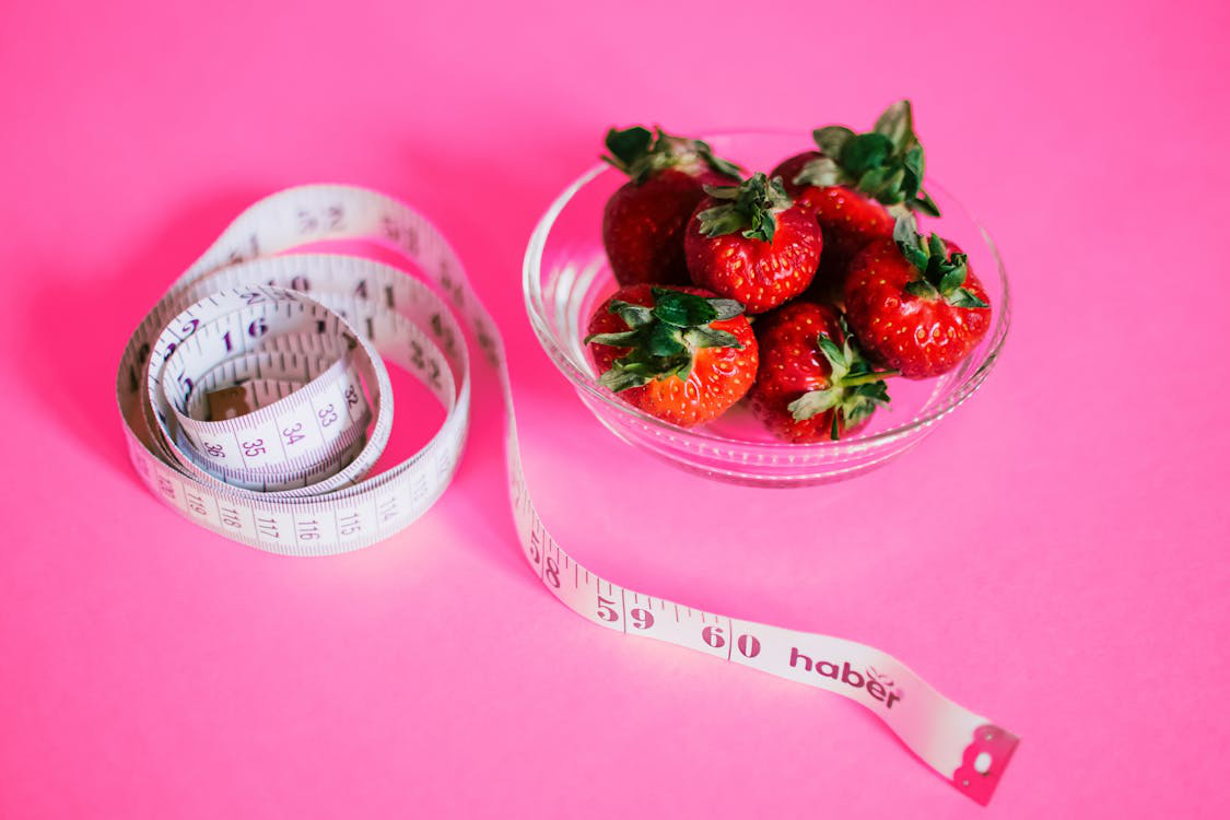 Fresh strawberries next to a measuring tape symbolizing healthy weight loss choices