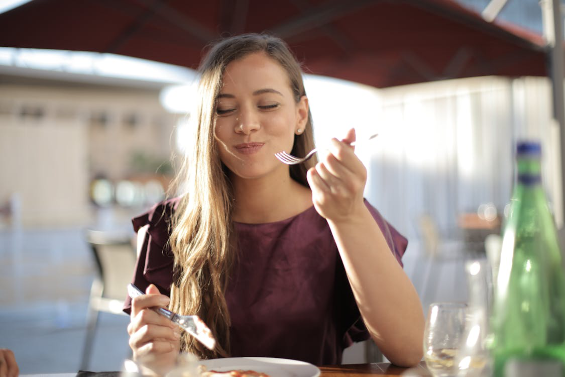 Woman smiling and enjoying her meal while eating slowly outdoors