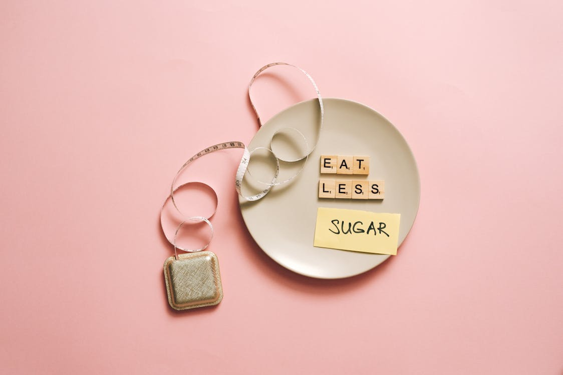 A plate with "EAT LESS" in Scrabble tiles and a "SUGAR" sticky note