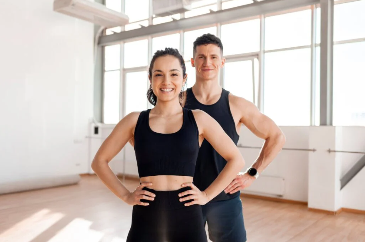  Fit, smiling man and woman standing confidently in a bright gym after achieving weight loss goals