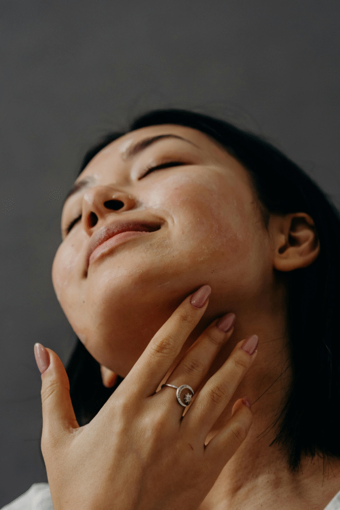 Woman touching glowing skin, showcasing the benefits of peptide therapy