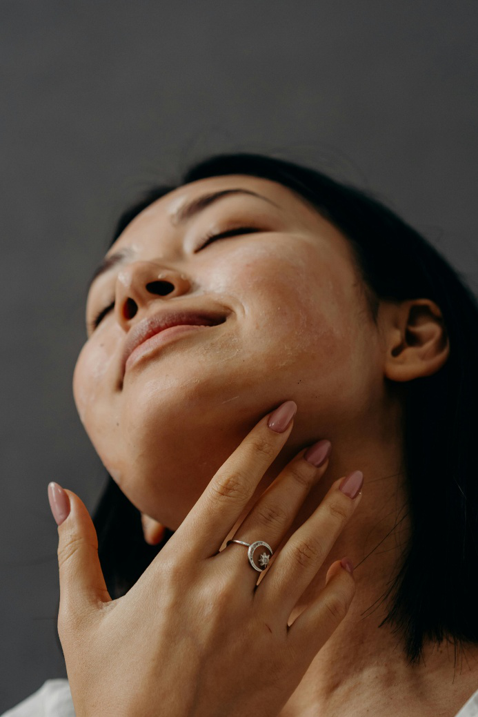 Woman touching glowing skin, showcasing the benefits of peptide therapy