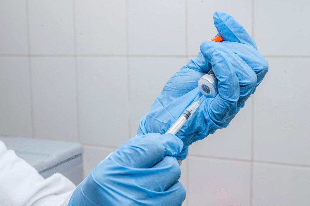 Gloved hands drawing medication into a syringe for injection