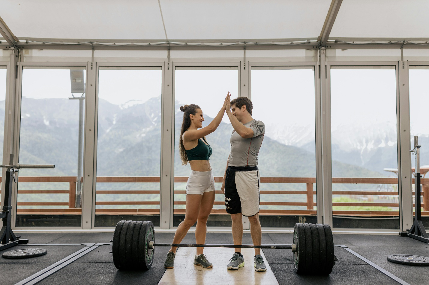Athletic man and woman celebrating a workout session with weights in the background