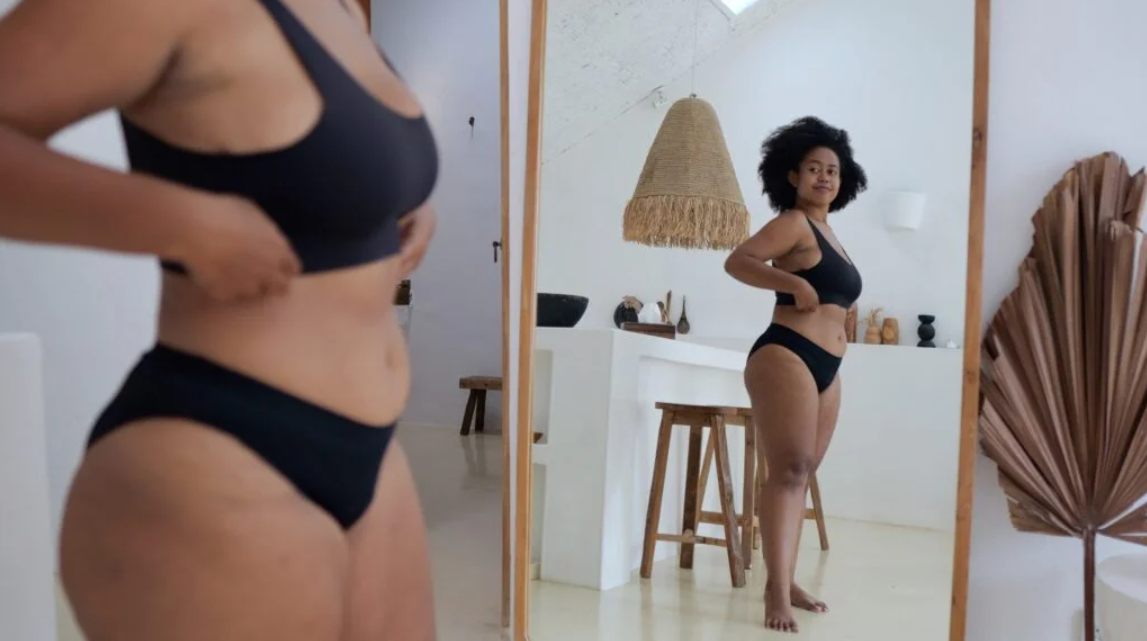  Woman admiring her body in front of a mirror, wearing black activewear