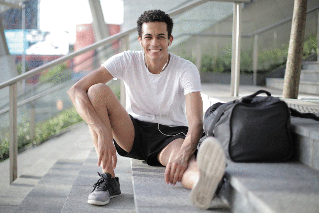 An image of a happy man listening to music while sitting on the stairs 