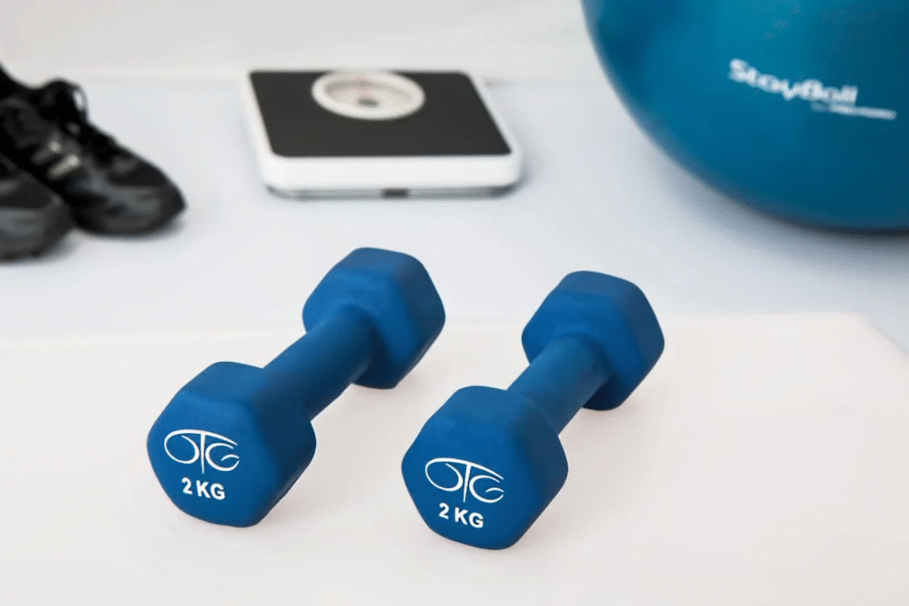 An image of dumbbells, a weight machine, shoes, and a large ball    
