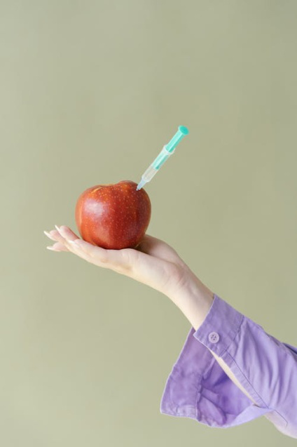An image of a person holding an apple with an injection inside