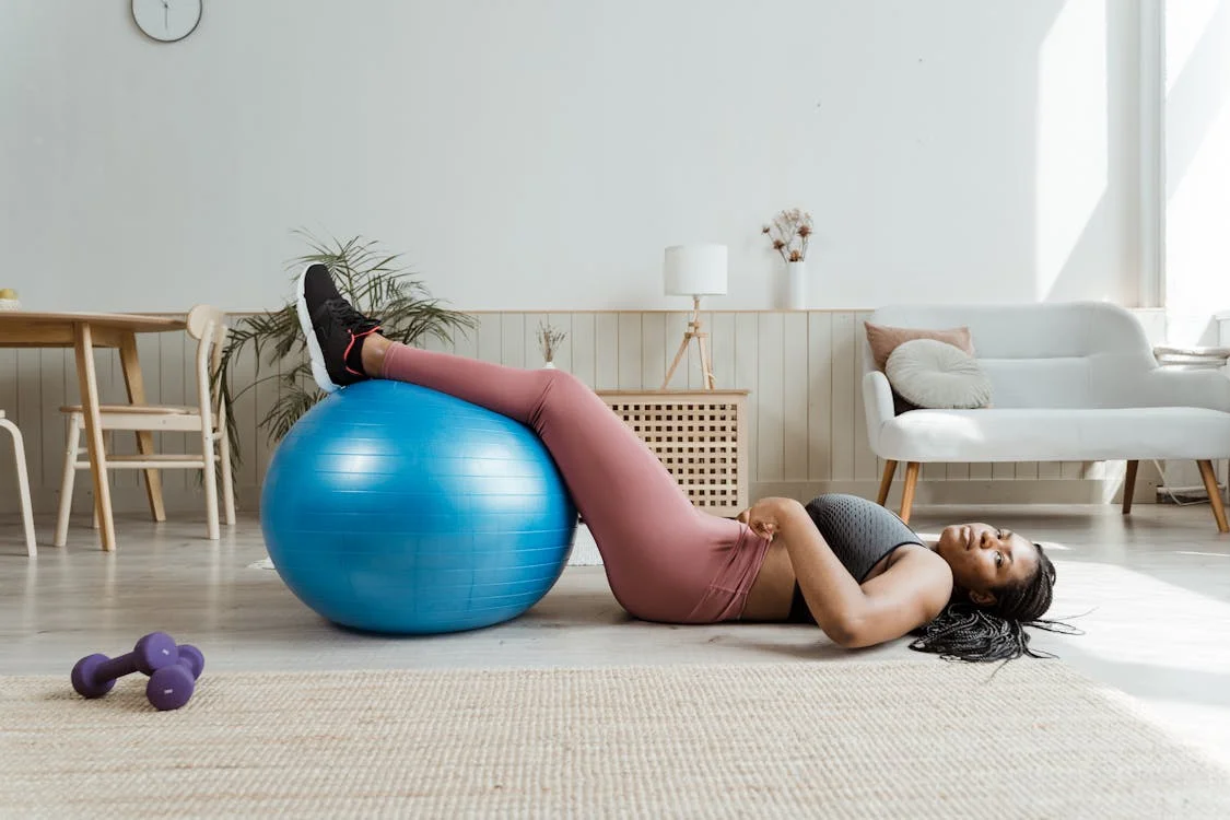 a woman resting on the floor with her legs on a gym ball.