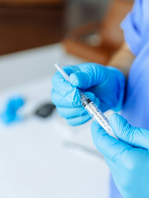 An image of a person wearing blue gloves holding an injection