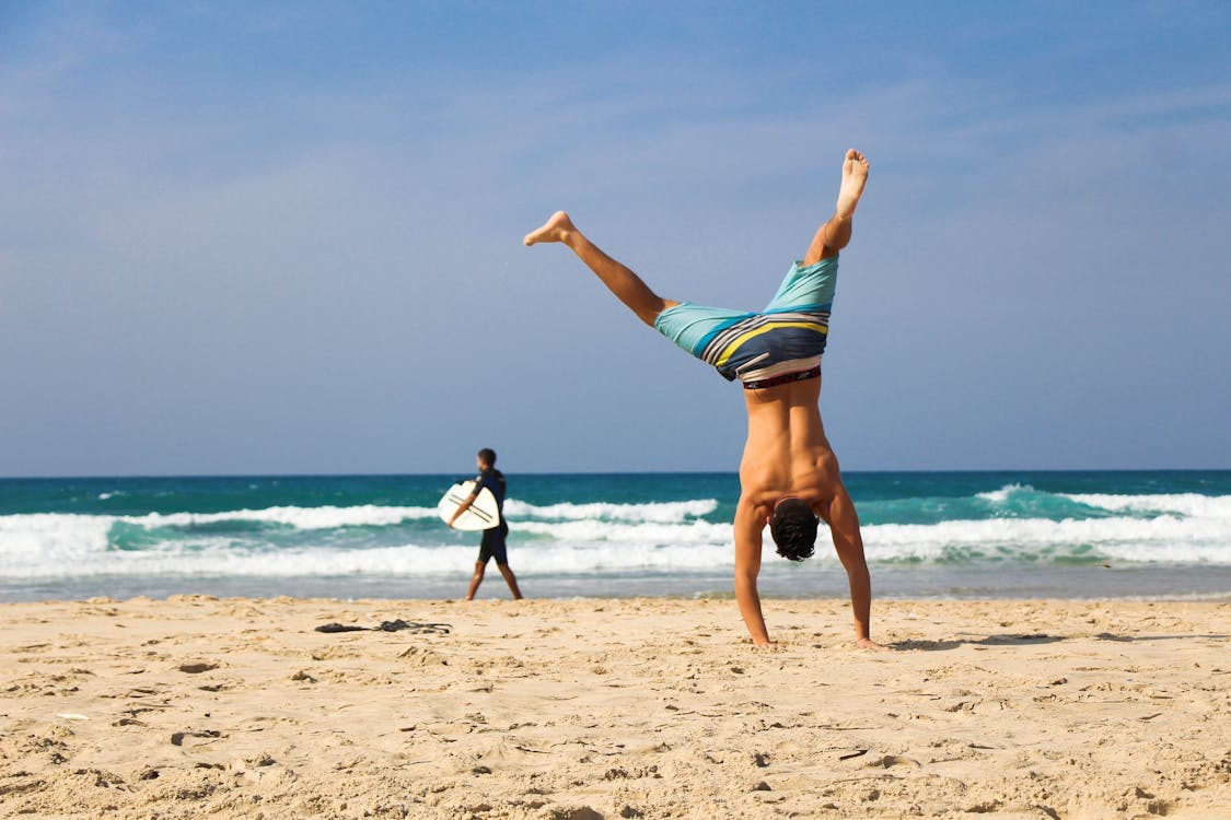  A man doing cartwheels on a beach.