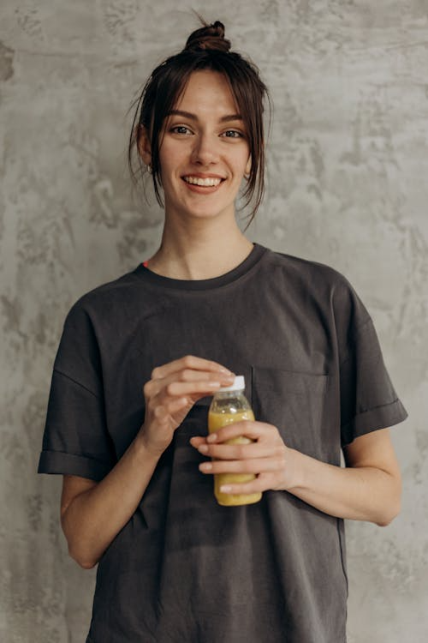 An image of a woman smiling while holding a healthy drink