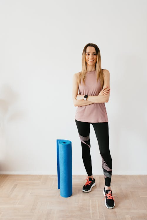  a woman standing next to a yoga mat. 