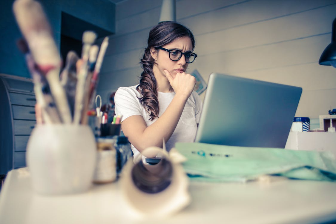 An image of a woman thinking while looking at a laptop