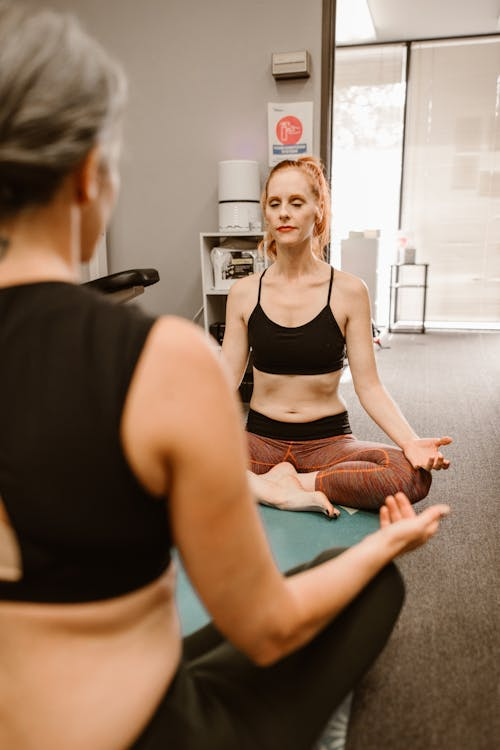  two women sitting in a yoga position. 