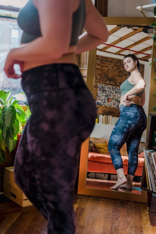 An image of a woman looking at herself in a full-length mirror