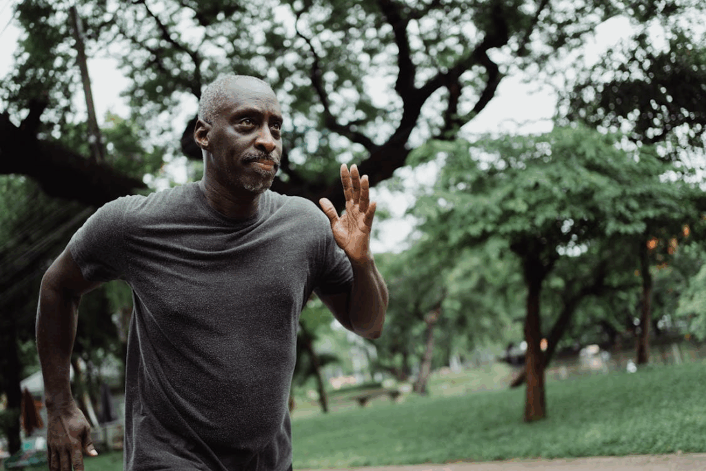Man jogging in a park with trees.
