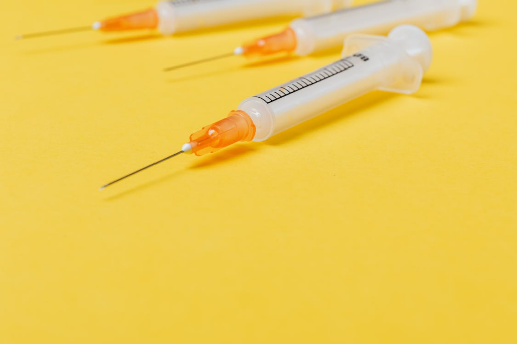 An image of empty syringes without their cover on a yellow surface