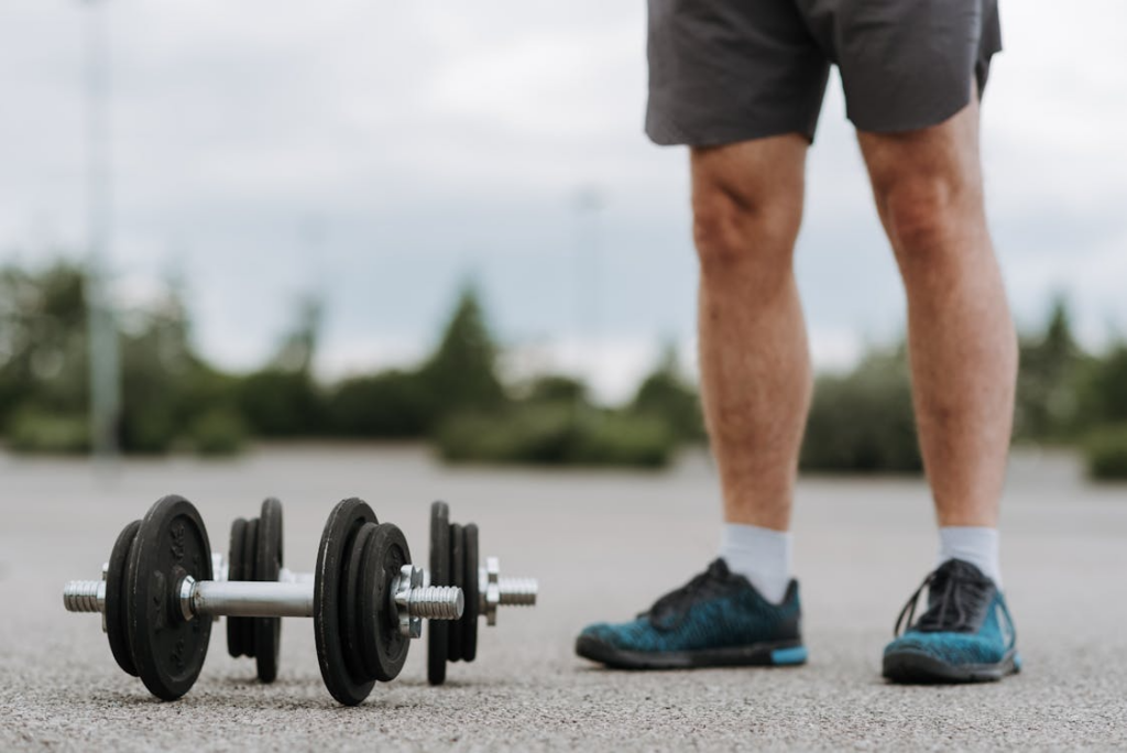 An image of a man standing near dumbbells