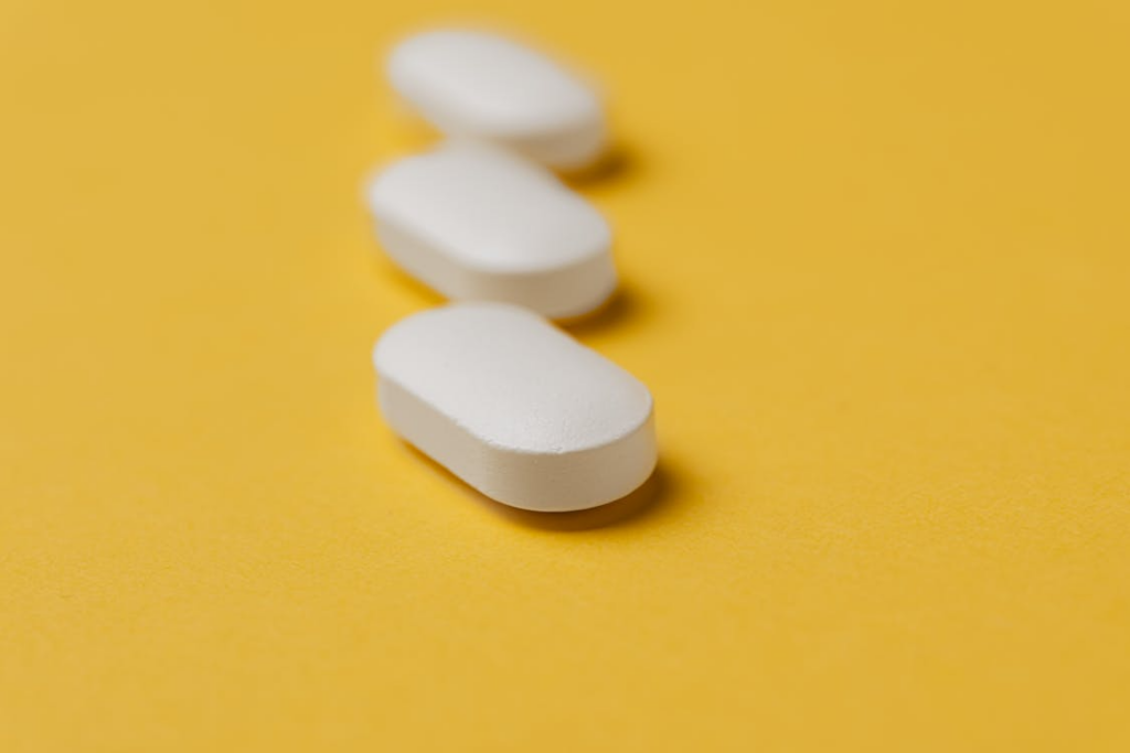  A number of white colored pills on a yellow background