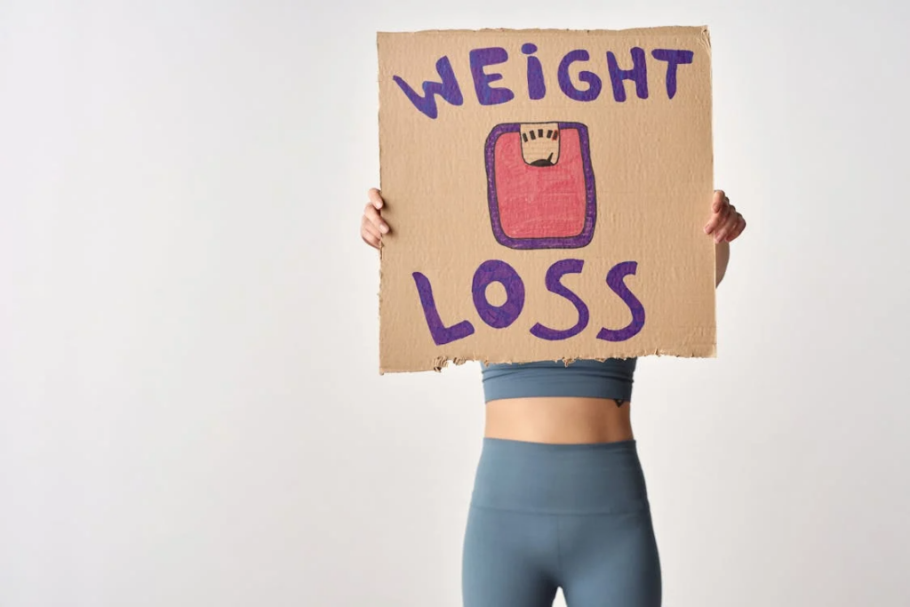 Person holding a cardboard sign with a weight loss message