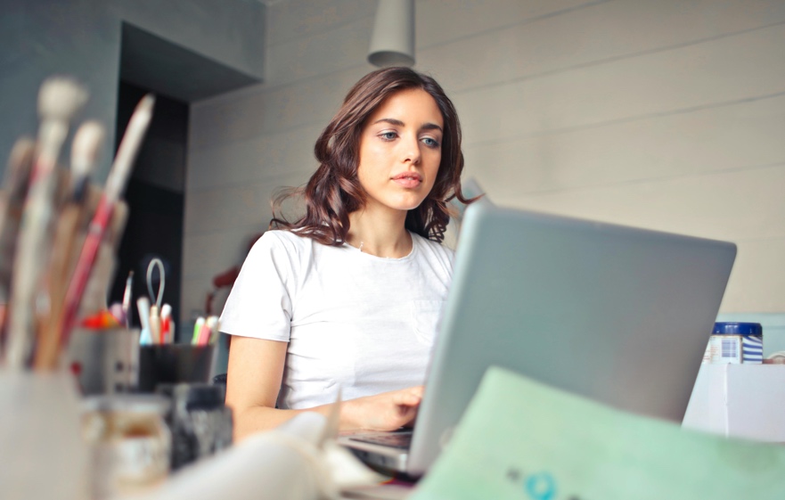 Adult working on a laptop with a focused expression in a clean workspace
